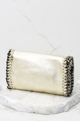 Back view of this clutch that features a front flap that has a silver magnetic closure, an inside zipper, a removable leather strap, and wide decorative stitching around the edges.