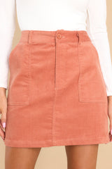 This terracotta colored skirt features a button and zipper closure, belt loops, two functional square pockets, and a velvety corduroy material throughout. 
