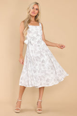 This white floral dress features a square neckline, zipper down the back, a removable self-tie at the waist, and a flowy skirt.