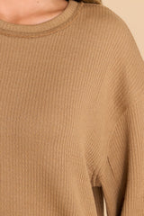Close up view of this top that features a round neckline, subtle bubble sleeves, a bottom hem that is approximately 2