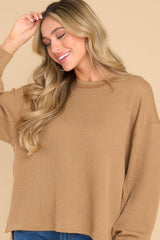 This camel colored top features a round neckline, subtle bubble sleeves, a bottom hem that is approximately 2
