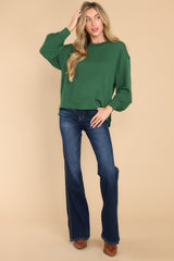 This green top features a round neckline, subtle bubble sleeves, a bottom hem that is approximately 2