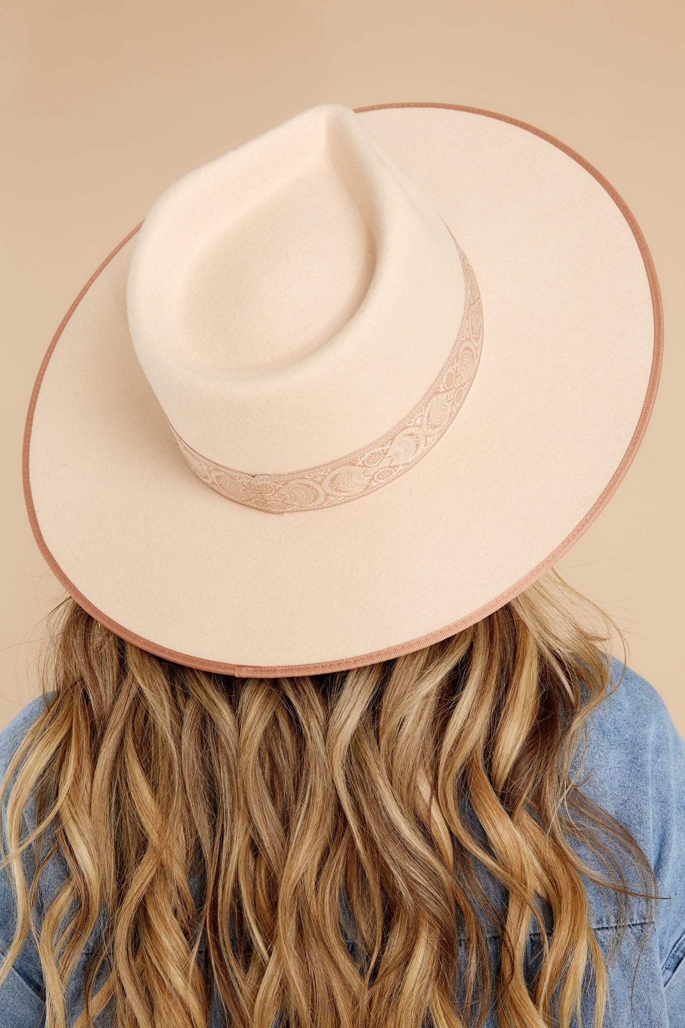 This ivory rancher hat featuring a stiffened wool fedora with a rigid crown design, and trimmed with a tonal grosgrain ribbon. 