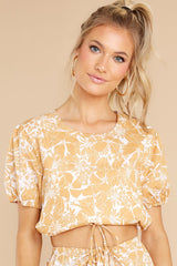 This white and yellow top features a cropped fit, puff sleeves, and scrunched waist with an adjustable tie.