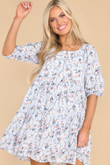 Front view of this dress that features a square neckline, elastic detail along the neckline, puff sleeves, and a flowy relaxed body.