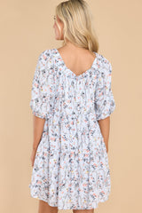 Back view of this dress that features a square neckline, elastic detail along the neckline, puff sleeves, and a flowy relaxed body.