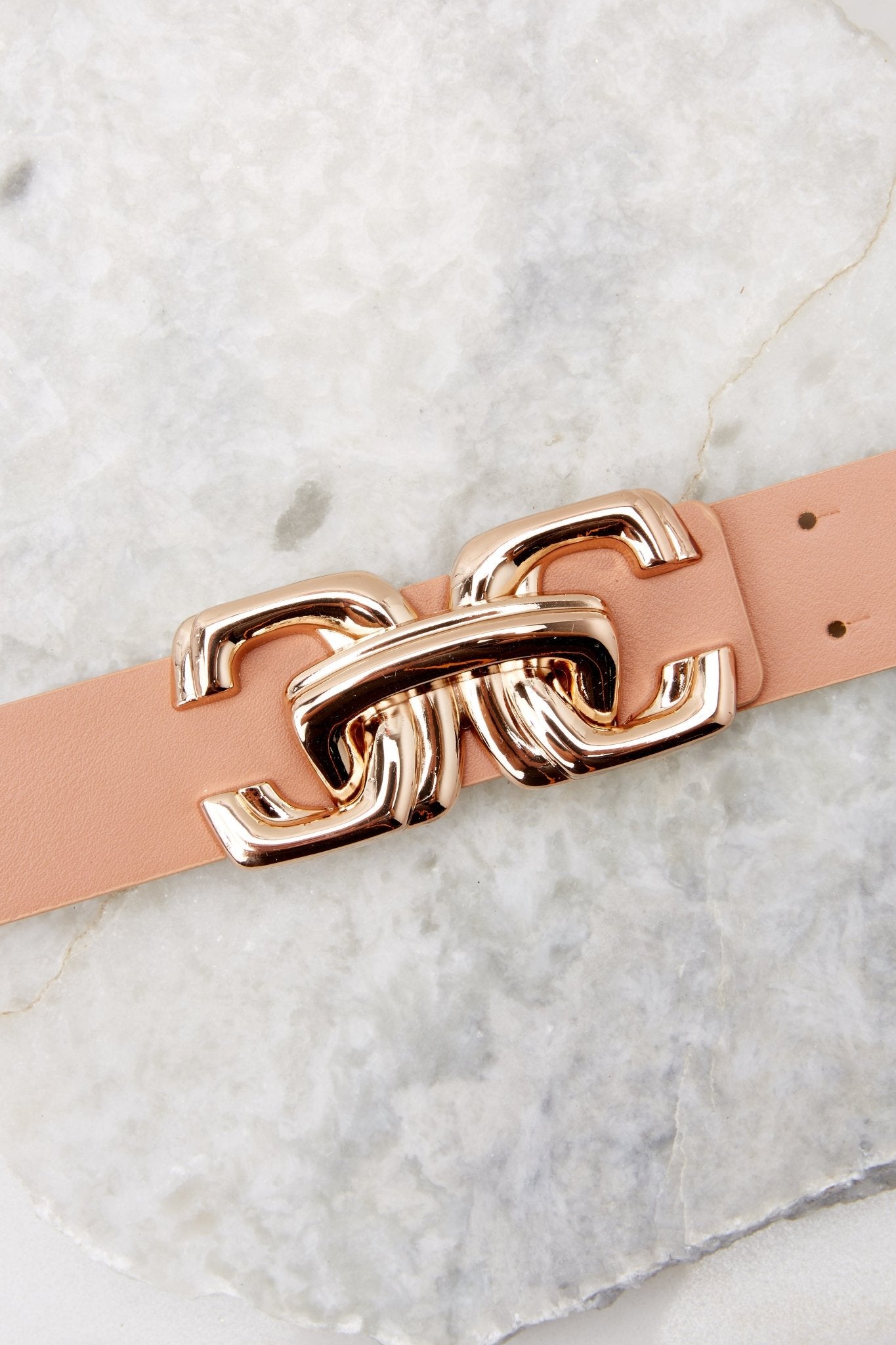This tan belt features a chain-link buckle closure with two prongs, a soft exterior, and gold hardware. 