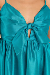 Close up view of this dress that features a sweetheart neckline with a keyhole detail on the bust, the bow at the bust is non-adjustable, adjustable spaghetti straps, zipper on the back, and a babydoll silhouette.