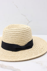 Close up view of this hat that features a straw design and a black ribbon around the base of the hat.