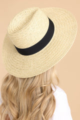 This ivory hat features a straw design and a black ribbon around the base of the hat.