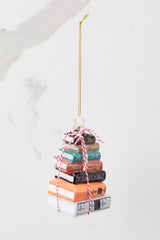 Front view of this ornament that features a design of stacked books with glitter accents and striped string. 