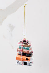 This multi-colored ornament features a design of stacked books with glitter accents and striped string. 