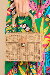 Front view of this bag that features gold hardware, a detachable gold shoulder strap, floral print design on the inside, and a twist lock closure.