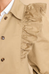 Close up view of this coat that features a collar neckline and ruffle detailing along the shoulders and bust area.