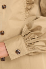 Close up view of this coat that features puff sleeves with buttoned cuffs, a self-tie around the waist for a custom fit, and two functional waist pockets.