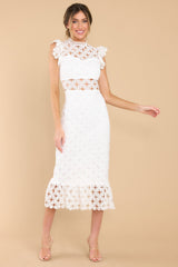 Front view of this crochet lace midi dress that features a high neckline with an illusion sweetheart neckline, ruffled shoulders, a peek-a-boo waistline which gives way into a sheath silhouette fit, and a flounced hem. Dress has a visible back zipper.