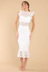 Front view of this crochet lace midi dress that features a high neckline with an illusion sweetheart neckline, ruffled shoulders, a peek-a-boo waistline which gives way into a sheath silhouette fit, and a flounced hem.