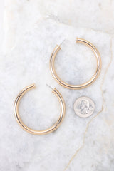 Gold hoop earrings shown compared to quarter for actual size. Earrings measure 2
