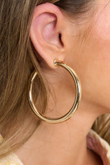 Model shown wearing hoop earrings that feature a gold design and a post-back closure