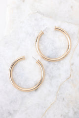 Overhead detailed view of hoop earrings that feature a gold design and a post-back closure