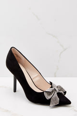 Outside view of black suede high heels featuring a skinny heel. 