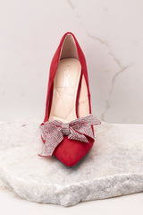 Front view of these heels that feature a red suede detail throughout the shoe with rhinestone covered bow and pointed toe.
