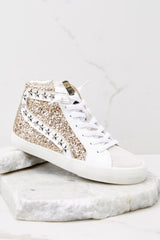 Close up view of these sneakers that feature a glittered body with star studs along the side, standard lace-up front, white laces, textile interior, a glitter base and side zipper.