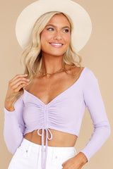 This lavender colored crop top features a scrunched center complimented by an adjustable self tie, a lower scoop neck, and a ribbed fabric.