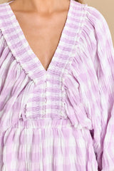 Close up view of this romper that features a deep v-neckline, dolman sleeves with elastic cuffs, smock stretch through the shoulders, and an elastic stretch waistband.