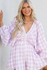 Front view of this romper that features a deep v-neckline, dolman sleeves with elastic cuffs, smock stretch through the shoulders, and an elastic stretch waistband.