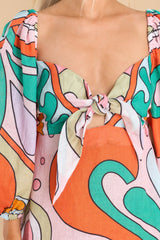 Close up view of this dress that features a sweetheart neckline with a self tie between the bust, a smocked stretched insert on the back, puff sleeves with elastic around the shoulders and cuffs, and a flowy body.