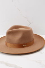 This brown rancher hat features a teardrop crown with an upturned brim and a band around the crown. 