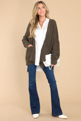 This green cardigan features a soft, chunky knit design, functional pockets, and small slits up the sides.