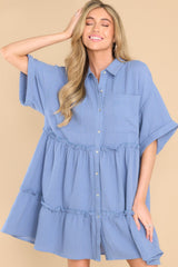 Front view of this dress that features a collared neckline, functional buttons down the front, functional pockets at the bust, short sleeves with folded cuffs, and ruffle detailing throughout the skirt.