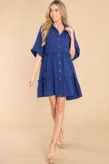 Full body view of  this dress that features a collared neckline, functional buttons down the front, functional pockets at the bust and short sleeves with folded cuffs.