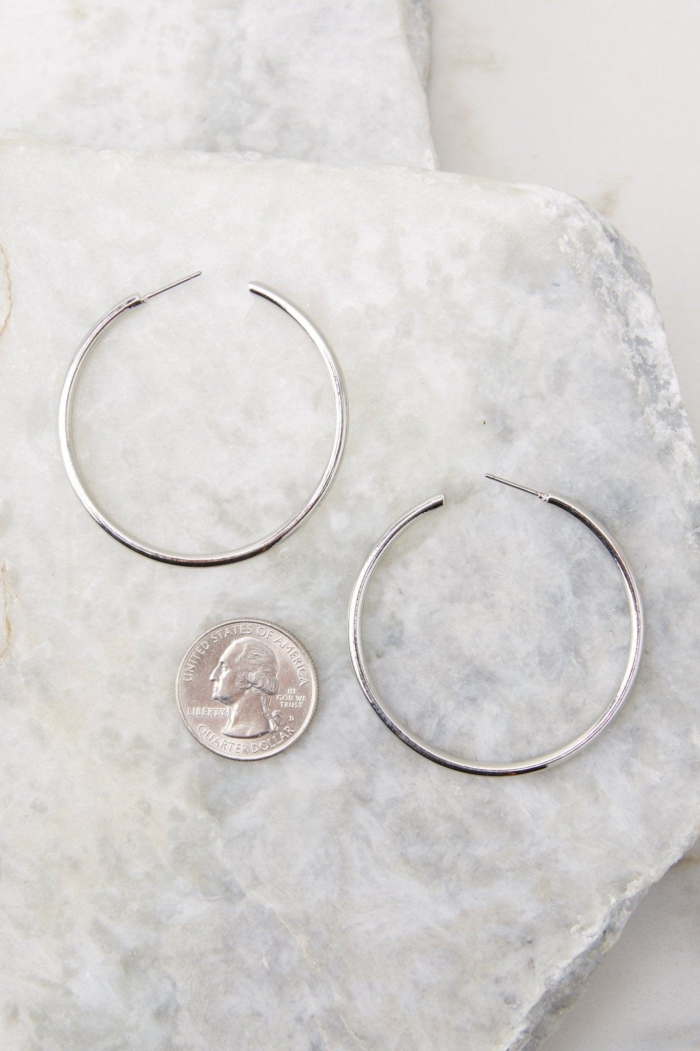 Detailed view of hoop earrings compared to quarter for actual size. Earrings measure 2.5