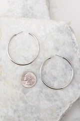 Detailed view of hoop earrings compared to quarter for actual size. Earrings measure 2.5