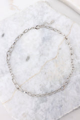Overhead view of necklace that features an alternating silver chain link pattern with the links varying in shape and texture and a lobster claw clasp.