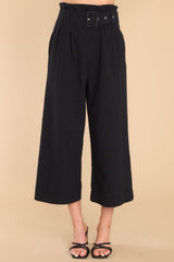 Front view of these pants that feature a high rise, a zipper and hook and eye closure, an adjustable belt, functional pockets, and a cropped wide leg design. 