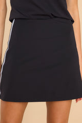 This black skort features a high-waisted design, an elastic waistband, shorts underneath the skirt overlay, and a stretchy material. 