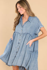 Front view of this dress that features a collared neckline, cuffed sleeves, buttons down the front, waist pockets, a flowy body, and a tiered detail on the back.