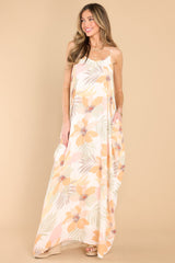 This ivory floral dress features a v-neckline, thin straps, waist pockets, and a flowy fit. 