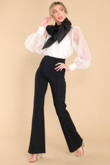 Full body view of  this top that features a high neckline with an oversized bow detail, a sheer puff sleeves with buttons at the cuffs, and is lined with a white tank.
