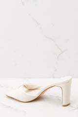 Inner-side view of  these heels that feature a square toe, a twisted strap across the top of the foot, a thin straight heel, and a slip on design.