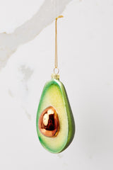 This green and gold ornament features a sparkly green avocado.