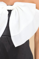 Close up view of this dress that features a strapless neckline and a large white bow detail at the center of the bust.