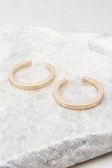 Close up view of chunky gold hoop earrings with a standard post back fastening. 