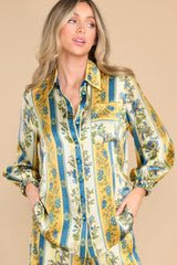 This multi-colored top features high collared neckline with pointed ends, balloon sleeves with elastic cuffs, fabric covered buttons closures, breast pocket, and curved hem.