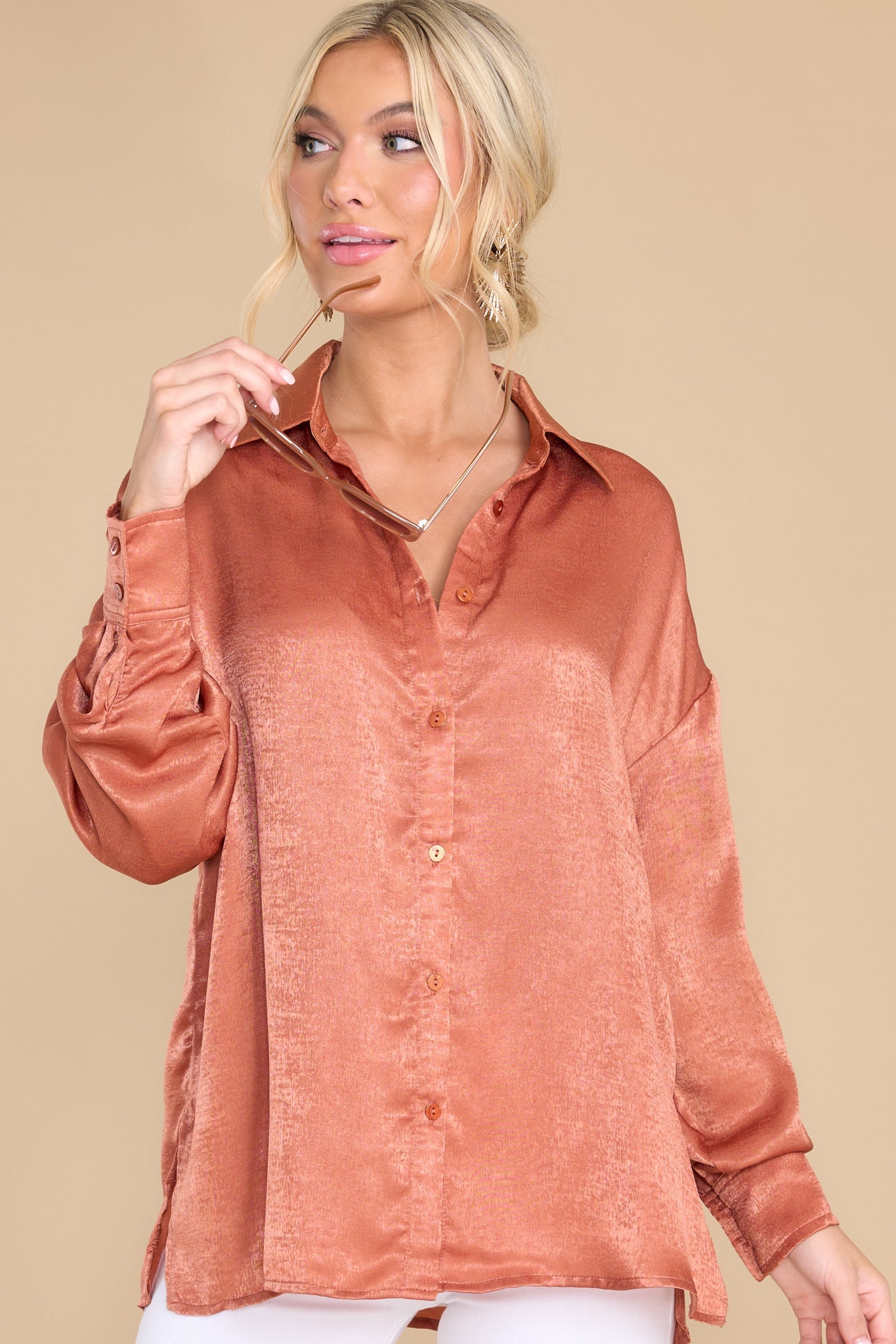 This terracotta colored top features a collared neckline, buttons down the front, buttons at the cuff, and a classic relaxed fit.