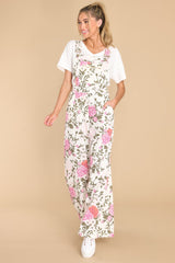 Full body view of these overalls that showcase the pink and green floral pattern.